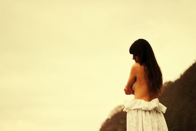 Side view of woman standing against sky during sunset