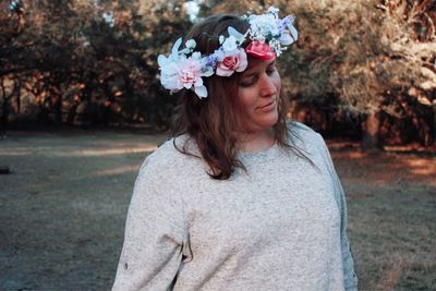 Portrait of beautiful young woman standing by flower plants