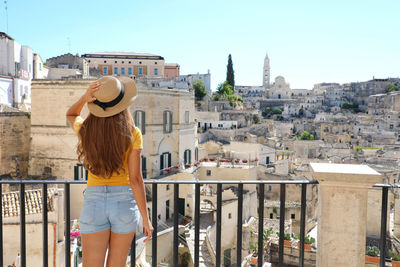 Rear view of woman standing against railing in city