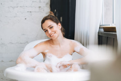 Young happy woman taking bath with foam at home, treat yourself