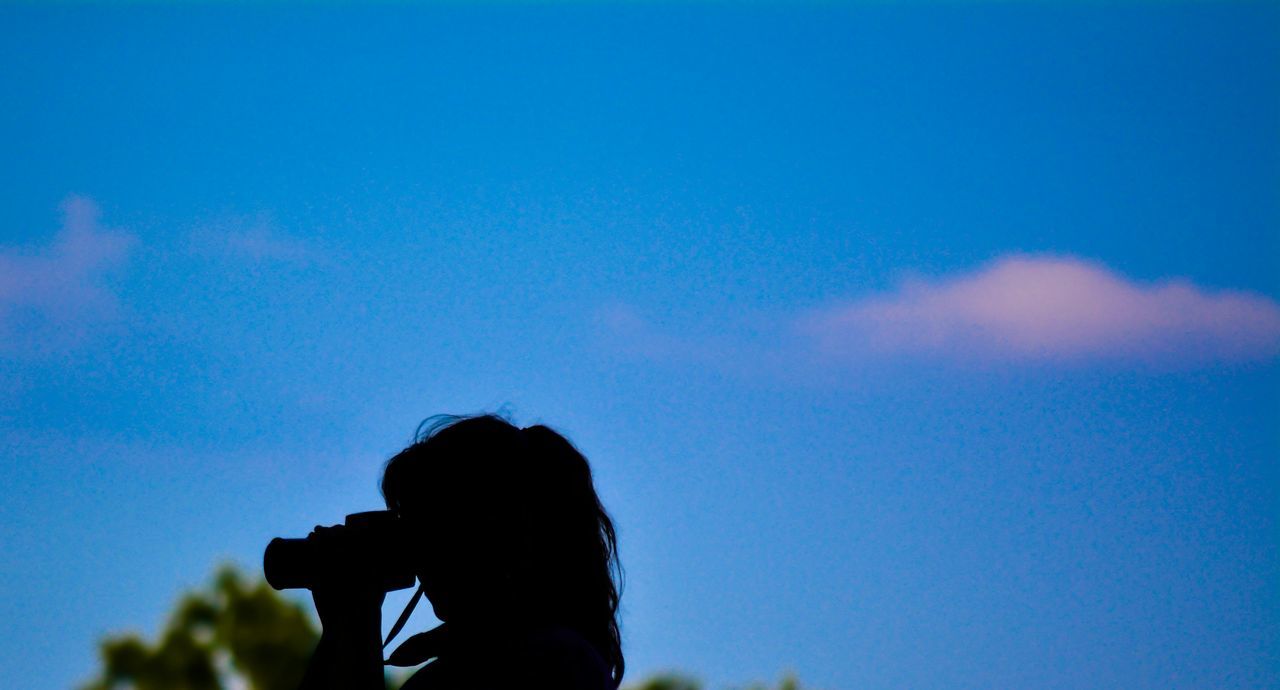 SILHOUETTE WOMAN PHOTOGRAPHING AGAINST BLUE SKY