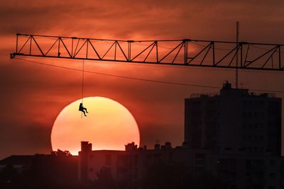 Silhouette crane against sky during sunset