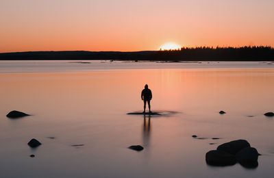 Silhouette woman walking on beach during sunset