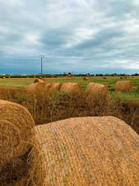 Hay bales on field against sky