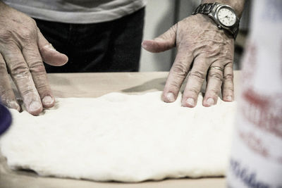 Midsection of man kneading dough in kitchen