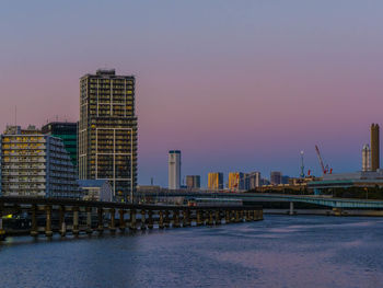 Bridge over river in city against clear sky