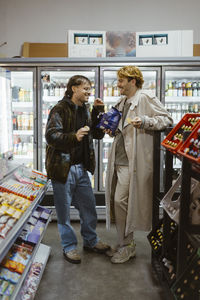 Happy gay couple talking with each other while having snacks at supermarket
