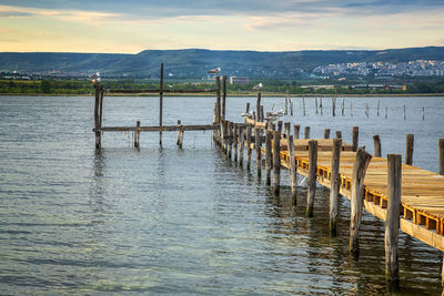 Wooden posts in lake against sky