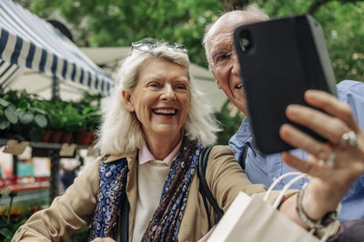 Happy senior woman taking selfie with man through smart phone
