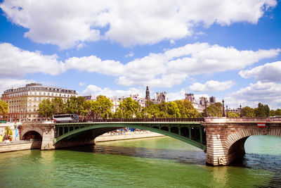 Arch bridge over river in city against sky