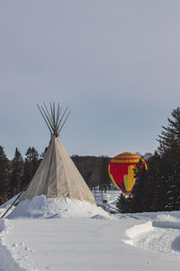 Windmill on snow covered land against sky