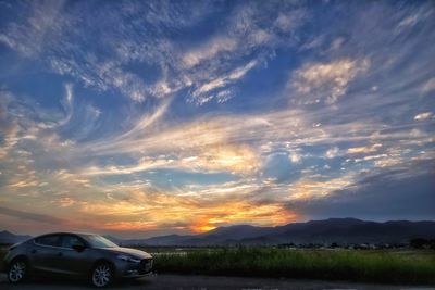 Cars on field against sky during sunset