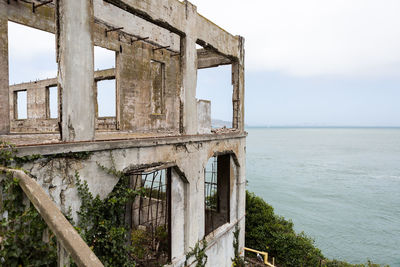 Abandoned built structure by sea against sky