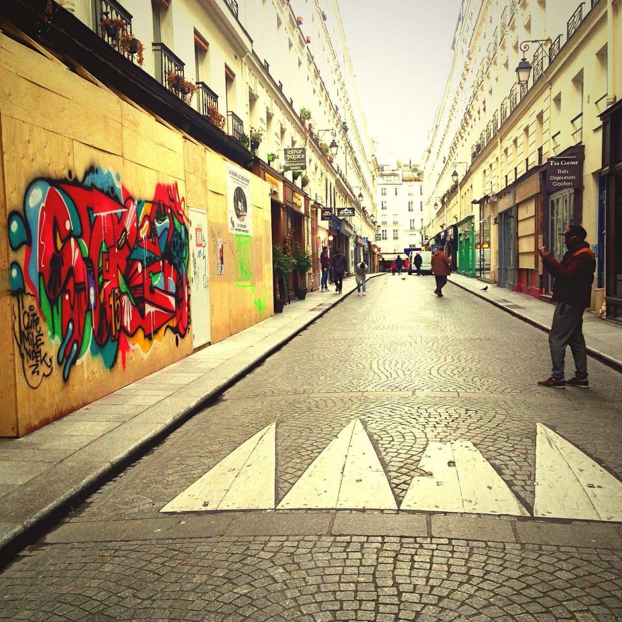 building exterior, architecture, built structure, street, lifestyles, men, person, cobblestone, text, city, leisure activity, walking, graffiti, city life, the way forward, full length, outdoors, sidewalk