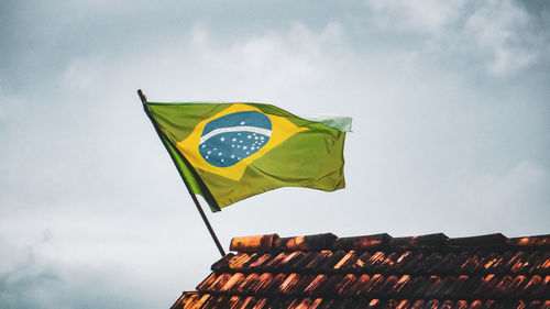 Low angle view of flag flags on roof against sky