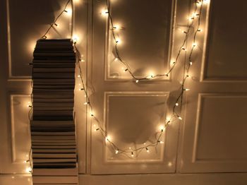 Illuminated lamp hanging at night pile of books