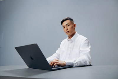 Portrait of businessman using laptop while sitting on table