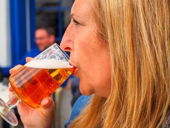 Profile view of woman drinking beer in wineglass