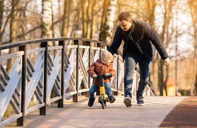 Happy father and son ride a bicycle on a bridge on a sunny day. having fun together with family