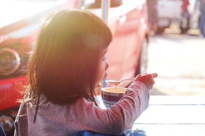Side view of girl drinking coffee with spoon
