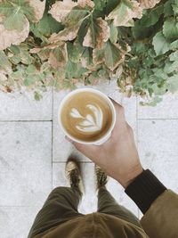 Low section of man holding coffee cup on footpath