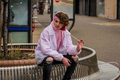 Boy holding electronic cigarette while sitting on bench