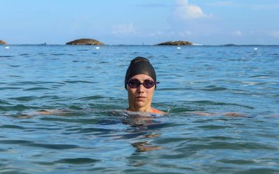 Portrait of woman swimming in sea against sky