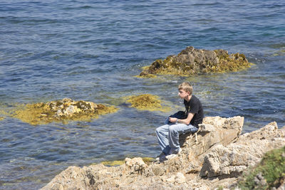 Thoughtful man sitting on rock by river