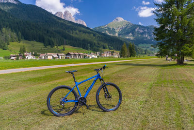 Bicycle parked on field by mountains against sky