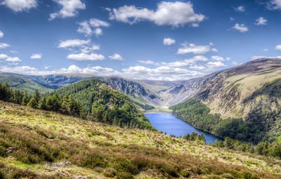 River amidst mountains against cloudy blue sky