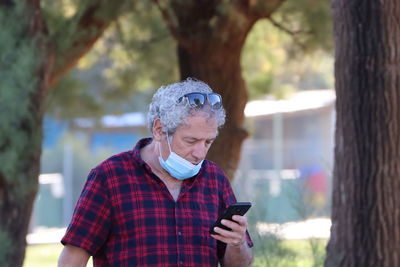 Man using phone while standing on tree trunk