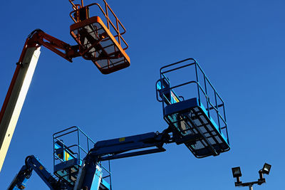 Low angle view of crane against clear blue sky