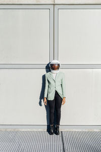 Businesswoman wearing space helmet in front of wall