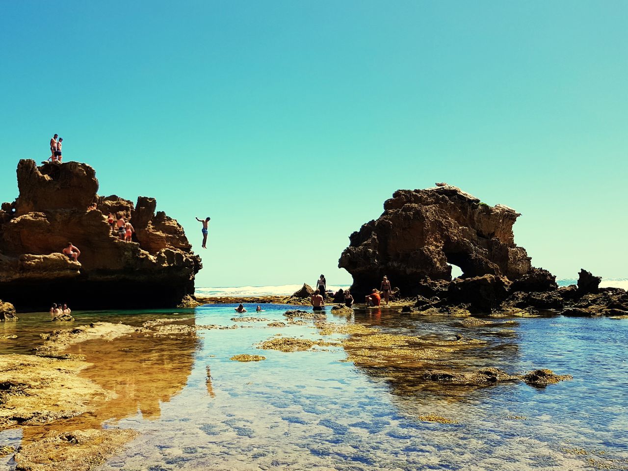 water, sky, rock, clear sky, sea, rock - object, group of people, solid, copy space, rock formation, land, nature, beach, scenics - nature, beauty in nature, day, waterfront, incidental people, blue, outdoors