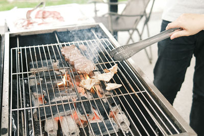 Person preparing food on barbecue grill