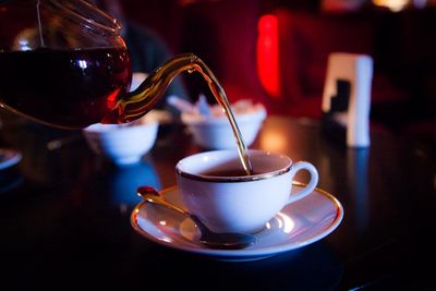 Close-up of tea being poured in cup on table in restaurant