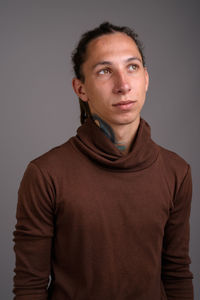 Portrait of young man standing against gray background