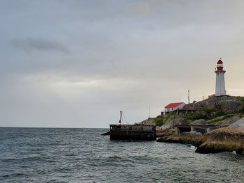 Lighthouse by sea against sky