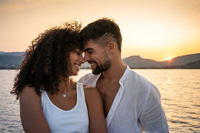 Young couple kissing against sky during sunset