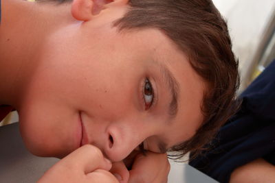 A relaxed child look in camera while he rests his head on one arm.