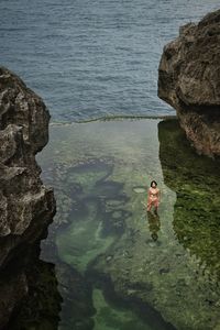 High angle view of woman on rock in sea