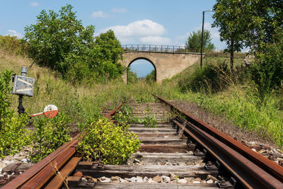 Railroad tracks by bridge against sky