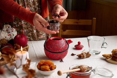 Cozy autumn days. woman brew tea in red teapot on the table with linen tablecloth. fall vibes.
