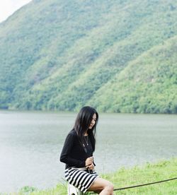 Full length of woman sitting by lake