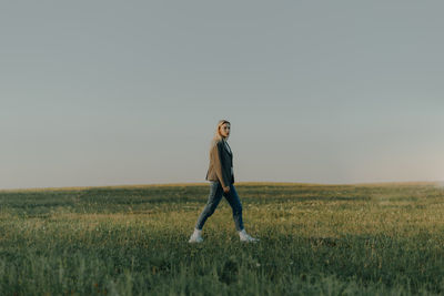 Full length of woman standing on field against clear sky