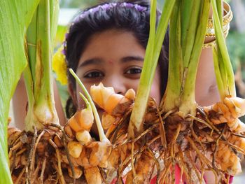 Portrait of girl holding turmeric plant on sunny day