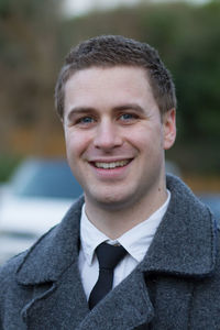 Close-up portrait of smiling young businessman standing outdoors