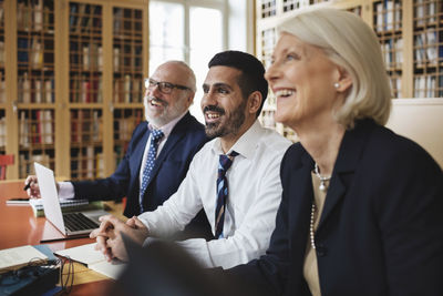 Happy male and female professionals listening in meeting