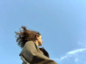 Portrait of young woman against blue sky