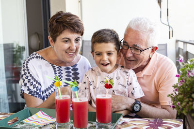 Smiling family looking juice glasses at home